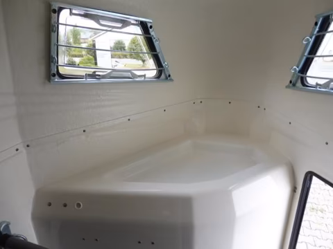 Innenraum eines Wohnwagens mit Fenster, weißen Wänden und installiertem Waschbecken.