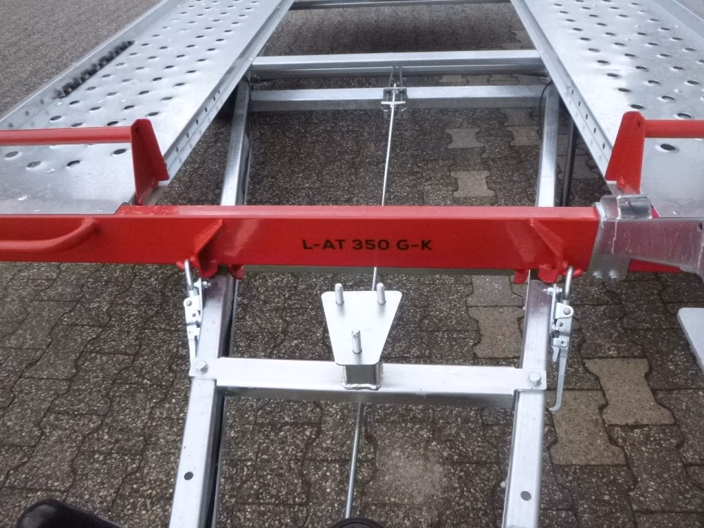 Aluminium-Dachleiter L-AT 350 G-K mit roten Querbalken und perforierter Oberfläche auf Pflastersteinen.