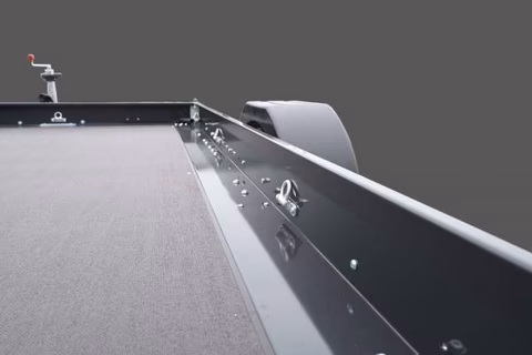 Nahaufnahme einer Ladefläche eines Pickup-Trucks mit Abdeckung und Befestigungssystem gegen grauen Hintergrund.