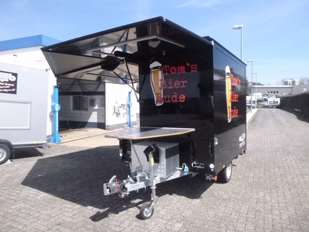 Tom's Bier Bude - schwarzer Verkaufswagen mit Getränkeangebot und ausfahrbarem Dach auf Parkplatz.