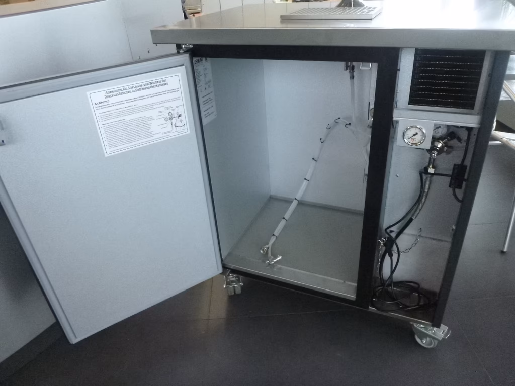 Offener Laborschrank mit Klimaregelung, Druckmessgerät und technischer Dokumentation auf der Tür.