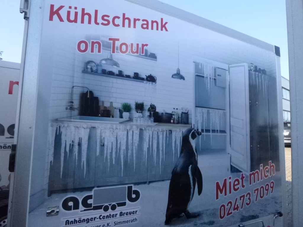 Werbung für mobile Kühlschränke mit Pinguin und Kontaktinformationen auf Anhänger.