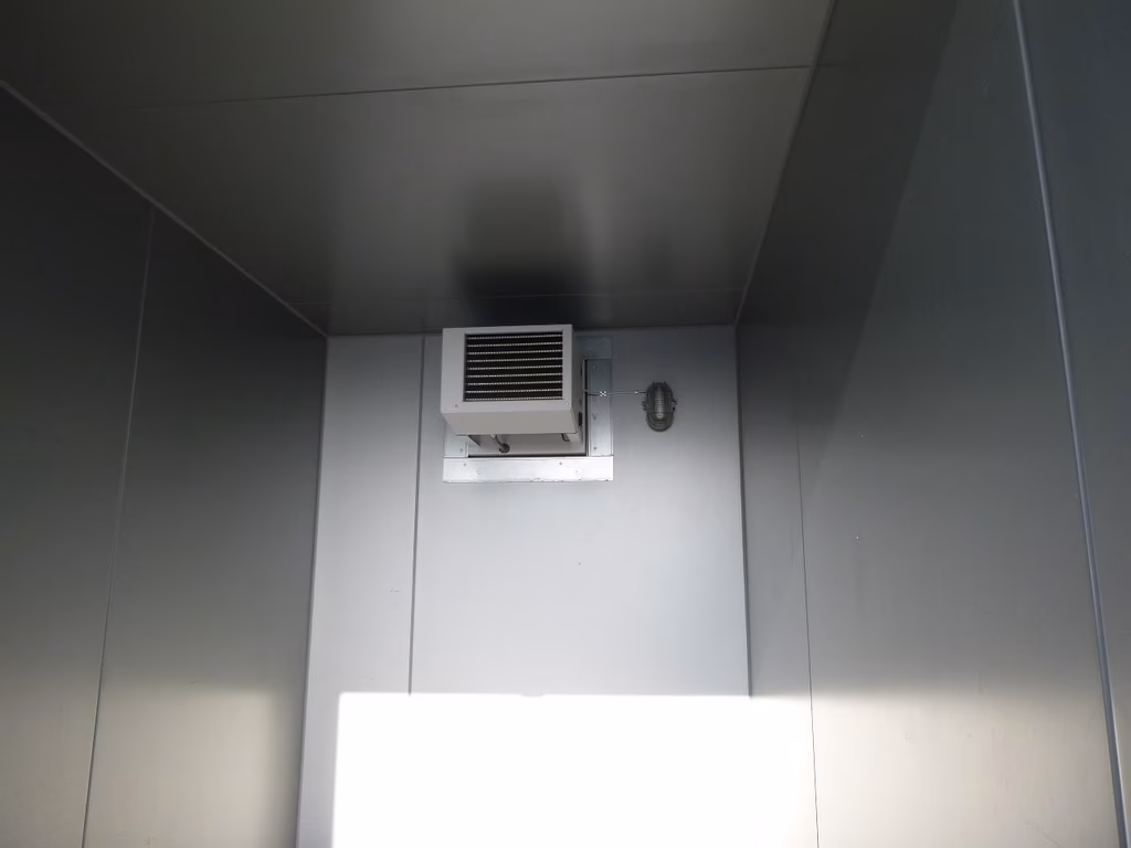 Kühlraum mit Klimaanlage an der Decke und Thermometer an der Wand.
