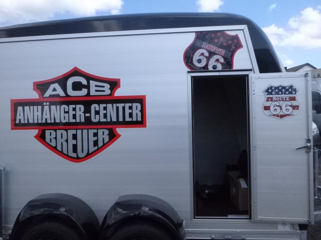 Wohnmobil mit "ACB Anhänger-Center Breuer" Logo und Route 66 Emblem auf der Seite.