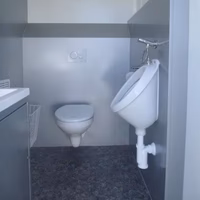 Modernes kleines Badezimmer mit Wandtoilette, Urinal und Waschbecken in Grau- und Weißtönen.