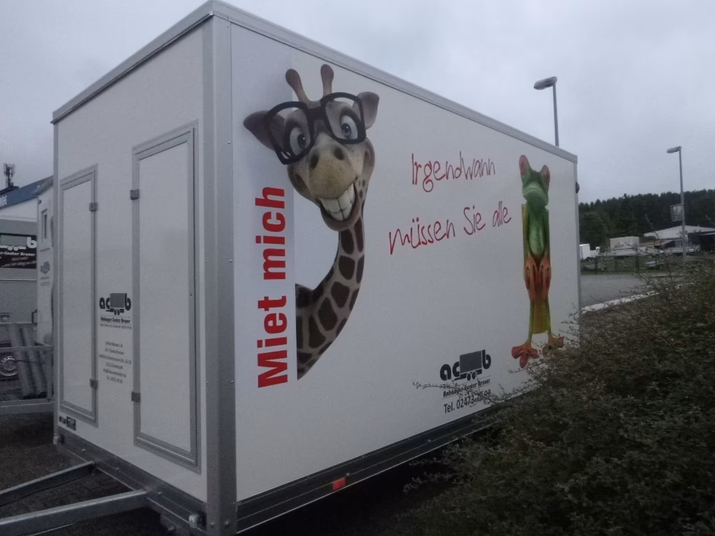Weißer Verkaufsstand mit lachender Giraffe, Schrift "Miet mich" und Gemüseabbildung.