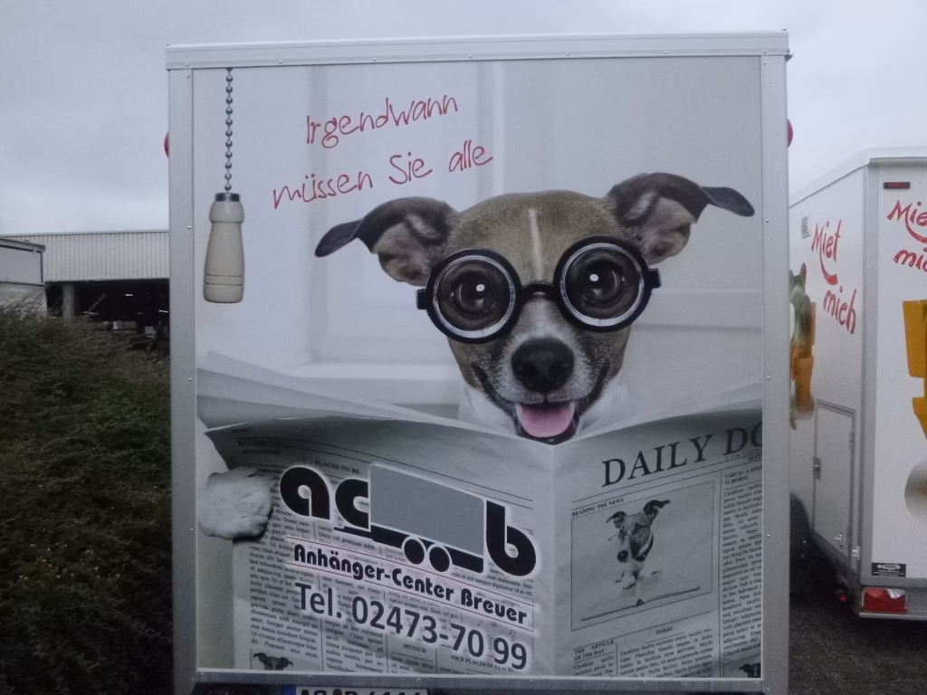 Hund mit Brille liest Zeitung auf Anhänger-Center-Breuer Werbung, Text "irgendwann müssen Sie alle"