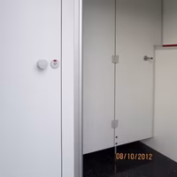 Modernes Badezimmer mit glaserner Duschkabine und weißen Wänden, Thermostat sichtbar.