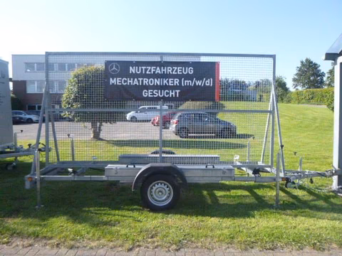 Anhänger mit Werbebanner für Mercedes-Benz Nutzfahrzeug Mechatroniker auf grüner Wiese.